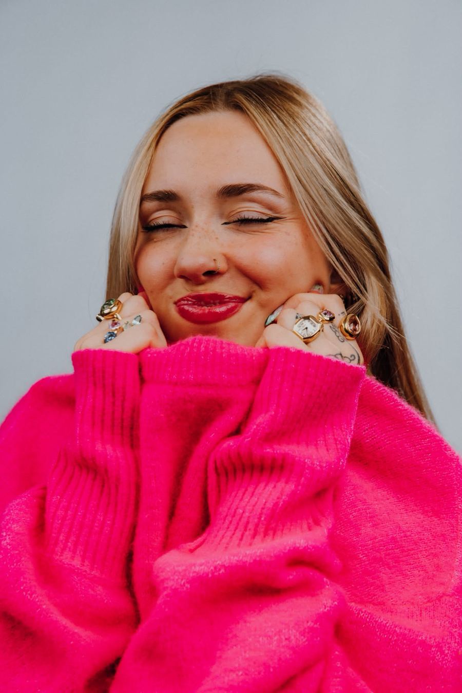 Cassandra, sourire aux yeux fermés, en pull rose